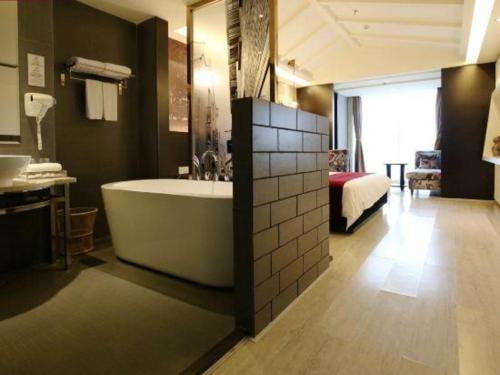 a bathroom with a tub and a bed in a room at Grand Nest Hotel (Tang Jia Wan Beach) in Zhuhai