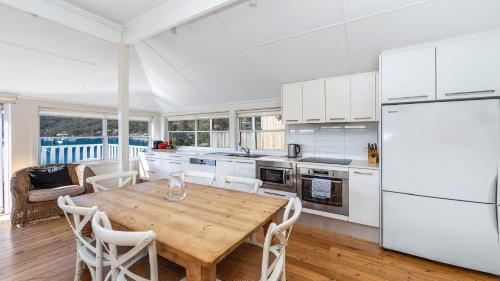 cocina con mesa de madera y electrodomésticos blancos en 'Torcello - Waterfront on the Bay' by HolidayCo, en Hardys Bay