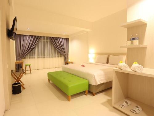 a bedroom with a bed and a green ottoman at Fovere Hotel Palangkaraya in Palangkaraya