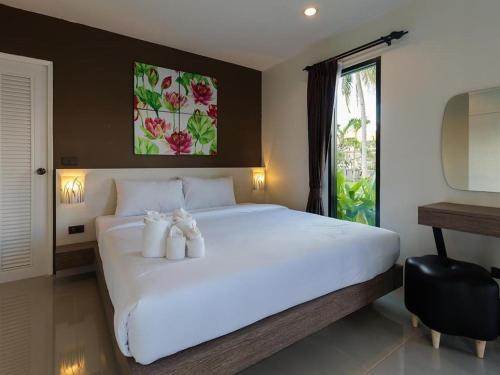 a bedroom with a large white bed with two teddy bears on it at Bua Tara Resort in Nong Prue