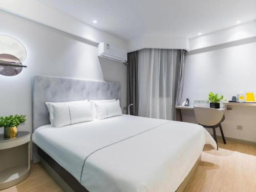 a bedroom with a large white bed and a chair at Magnotel Shanghai Henglong Plaza in Shanghai