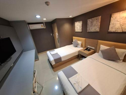 a hotel room with two beds and a flat screen tv at Collection O Pratunam 19 Hotel in Bangkok