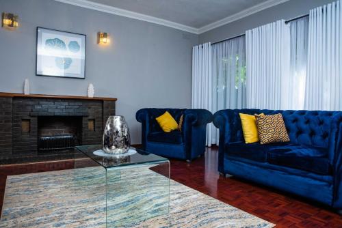 a living room with two blue couches and a fireplace at Imani Guest House in Bulawayo