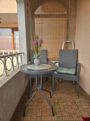 a table and two chairs and a vase with flowers on a balcony at Прекрасные апартаменты с видом на море в центре in Byala