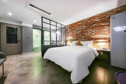 a bedroom with a white bed and a brick wall at Cheongju Maryjane Hotel in Cheongju