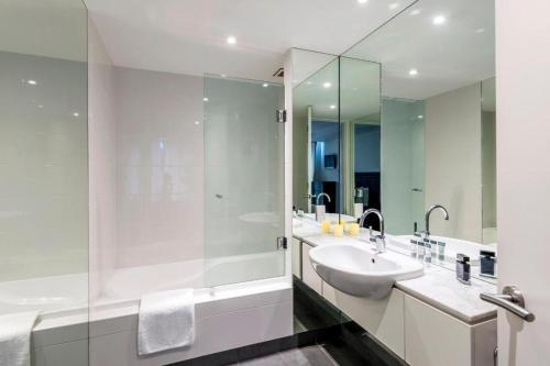 a white bathroom with a sink and a shower at Oaks Queenstown Club Suites in Queenstown