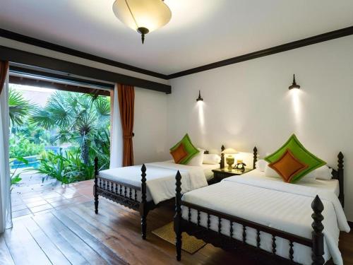 deux lits dans une chambre avec une grande fenêtre dans l'établissement Angkor Village Resort & Spa, à Siem Reap
