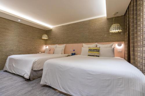 two beds in a hotel room with white sheets at 里萊行旅 - Lilai Motel in Taoyuan