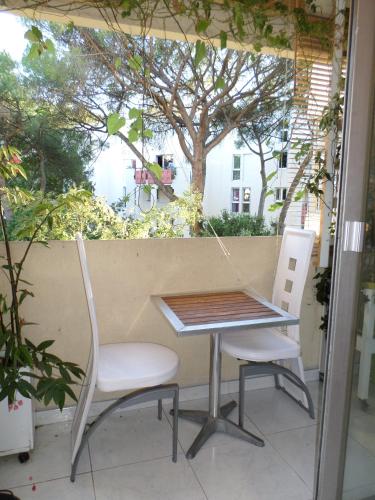 une table et deux chaises sur un balcon avec un arbre dans l'établissement Le Val Fleuri, à Sète