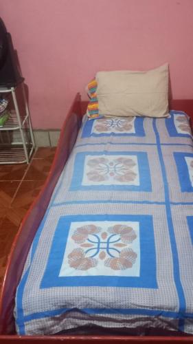 a bed with a blue and white blanket on it at Casa Rústica Rancho de Lía- Vacacional in Orotina