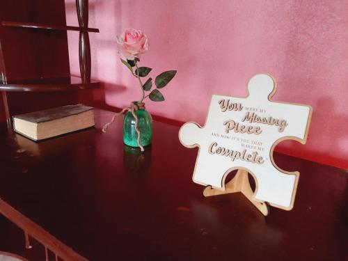 a wooden cross on a table with a rose in a vase at Casa Rústica Rancho de Lía- Vacacional in Orotina