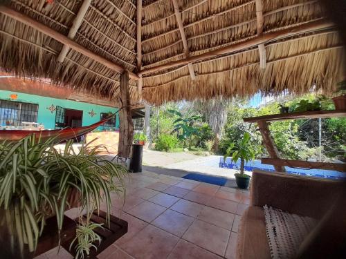 an open patio with a straw roof and plants at Casa Rústica Rancho de Lía- Vacacional in Orotina