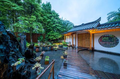 a house with a wooden deck with potted plants at Dujiangyan Irrigation Project Puruna Hot Spring Hotel Panda Valley Store in Dujiangyan