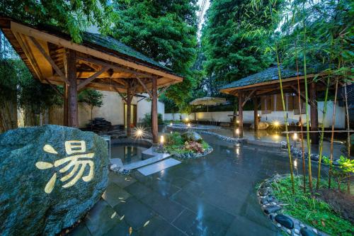 a garden with a pavilion and a large rock at Dujiangyan Irrigation Project Puruna Hot Spring Hotel Panda Valley Store in Dujiangyan