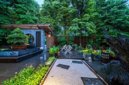 a garden in the rain with trees in the background at Dujiangyan Irrigation Project Puruna Hot Spring Hotel Panda Valley Store in Dujiangyan