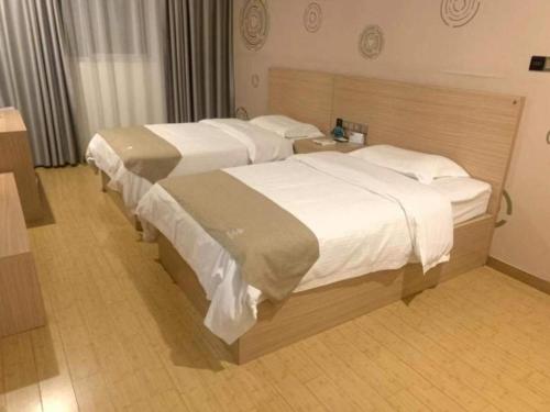 deux lits dans une chambre d'hôtel avec des draps blancs dans l'établissement GreenTree Inn Yancheng Dongtai Fuan Town Express Hotel, à Anfeng