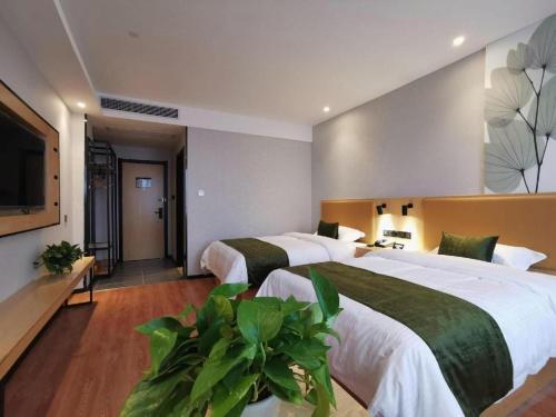 a hotel room with two beds and a flat screen tv at GreenTree Inn Ganzhou Gan County Bus Station in Ganzhou