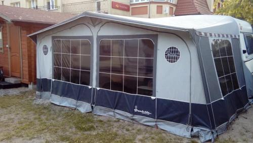 a blue and white tent in a yard at Domki letniskowe Przyczepy kempingowe Zacisze Mielno in Mielno
