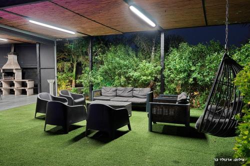 a patio with a couch and chairs and a swing at Campanga nera - ארבע בקתות מהממות עם בריכה מחוממת וג'קוזי in Yarka