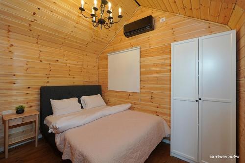 a bedroom with a bed in a wooden cabin at Campanga nera - ארבע בקתות מהממות עם בריכה מחוממת וג'קוזי in Yarka