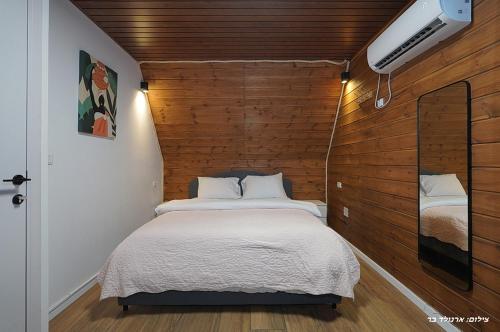 a bedroom with a bed with a wooden wall at Campanga nera - ארבע בקתות מהממות עם בריכה מחוממת וג'קוזי in Yarka