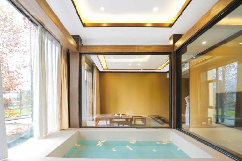 a bath tub in a room with a large window at Dujiangyan Irrigation Project Puruna Hot Spring Hotel Panda Valley Store in Dujiangyan
