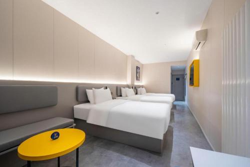 a hotel room with two beds and a yellow table at 7 Days Inn Qingdao Shandong Road Zhenning Overpass Branch in Qingdao