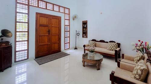 a living room with a door and a couch and a table at Badhram Homestay 4bhk in Alleppey