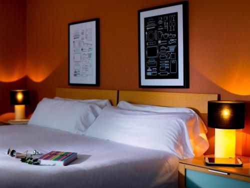 Un dormitorio con una cama con dos lámparas y un libro. en The Cookbook Gastro Boutique Hotel & SPA, en Calpe