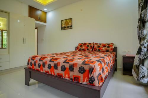 a bedroom with a bed with an orange and black comforter at Badhram Homestay 4bhk in Alleppey