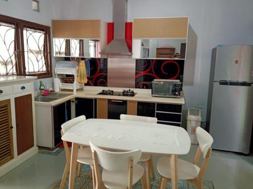 a kitchen with a white table and white chairs at Stylish House Near Pakuwon Mall in Kejayan