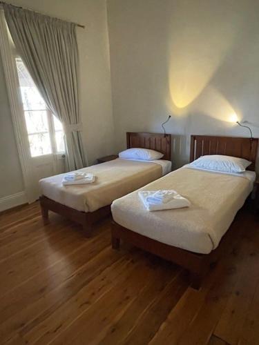 two beds in a room with wooden floors and a window at Eddy's of Canowindra in Canowindra