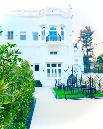 a white building with chairs in front of it at Grand Villa in Amritsar