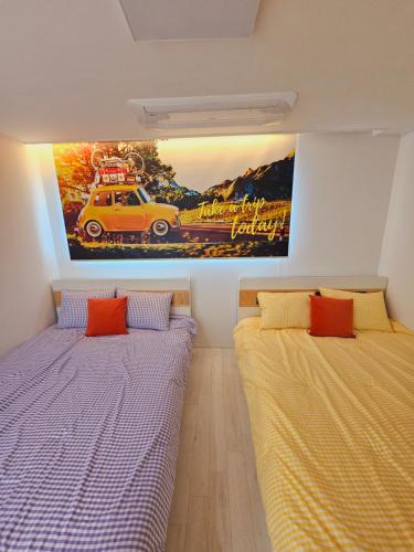 two beds in a room with a painting on the wall at New 패밀리 & 친구 여행 모임 청결하고 쾌적한 넓은 신축아파트 주차 편리 쓰리룸 in Bucheon