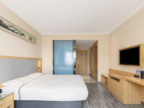 a bedroom with a large white bed and a television at City Comfort Inn Beihai RT-Mart High Speed Railway Station in Beihai