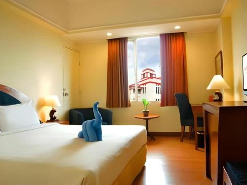 a hotel room with a bed with a blue dinosaur on it at Hotel Horison Arcadia Heritage Surabaya in Surabaya