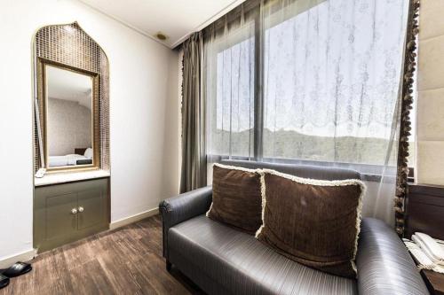 a living room with a couch and a mirror at Nostalgia Hotel in Paju