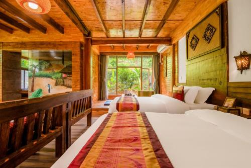 a bedroom with two beds and a large window at Dai House in Xishuangbanna Village in Menghan