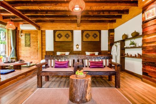 a room with wooden furniture and a table with purple pillows at Dai House in Xishuangbanna Village in Menghan
