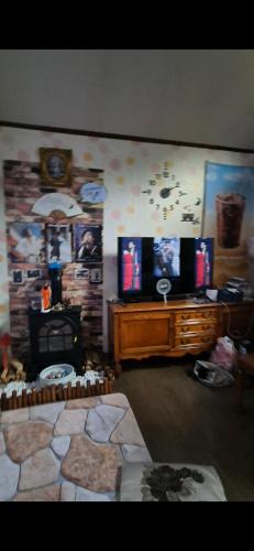 a living room with a tv and a stone wall at Gilson Story Pension in Pyeongchang 
