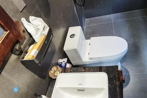 a bathroom with a white toilet and a trash can at Dai House in Xishuangbanna Village in Menghan
