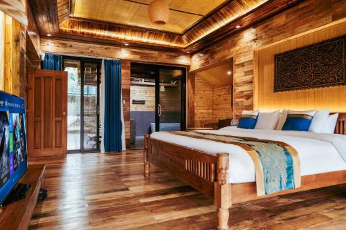 a bedroom with a large bed in a room with wooden walls at Dai House in Xishuangbanna Village in Menghan
