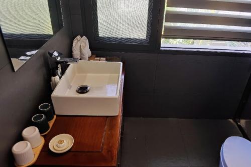 a bathroom with a white sink and a window at Dai House in Xishuangbanna Village in Menghan
