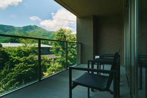 a balcony with two chairs and a view of the mountains at Hakone Hisui in Hakone