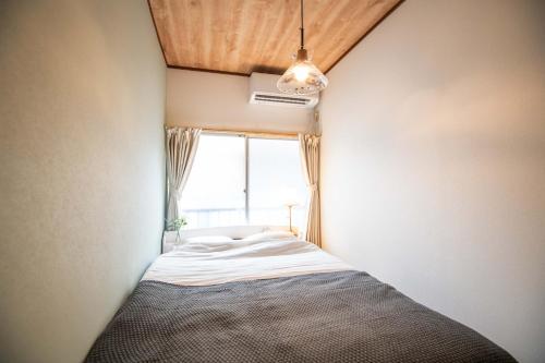 a small bed in a room with a window at Scent of Asia in Yokohama