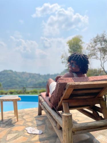 a woman sitting on a bench next to a pool at Nyanja View Resort in Fort Portal