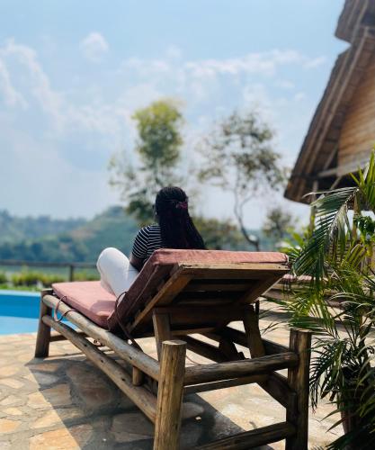 a woman sitting on a bench by a pool at Nyanja View Resort in Fort Portal