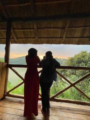 two women standing on a balcony looking out at the mountains at Nyanja View Resort in Fort Portal