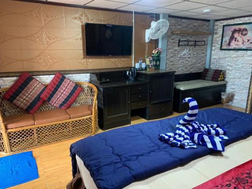 a living room with a large blue couch and a tv at Wanghin Bungalow in Surat Thani