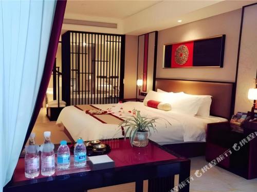 a hotel room with a bed and a table with water bottles at Yuan Culture Hotel Shenzhen World Shajing in Shenzhen
